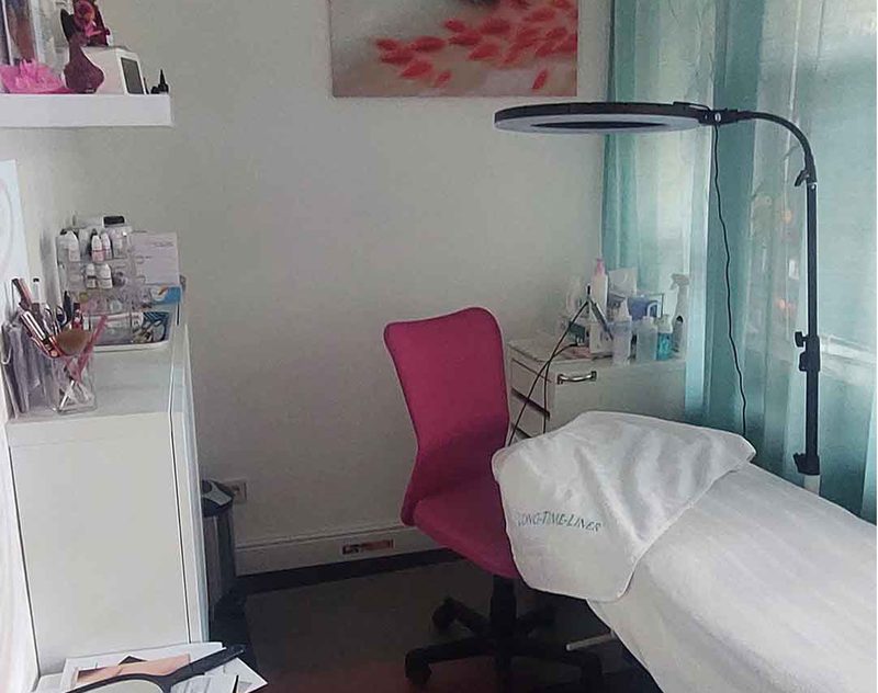 Behandlungszimmer 1 mit pinkem Stuhl und Liege